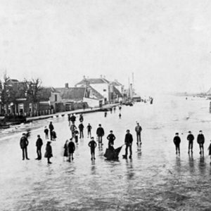 Op de achtergrond de directeurswoningen van de leerlooierij met aan de overkant van het water droogschuren van de dakpannen- en tegelfabriek D.van Oordt & Co. Links vooraan, dichter bij de Oude Rijn, liggen karakteristieke kleine dorpswoningen. Foto uit biografie Bloem : Van alle dingen los; Bart Slijper